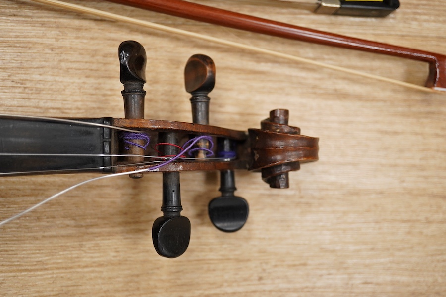 A late 19th century German violin, body 35cm long, and two bows. Condition - poor to fair.